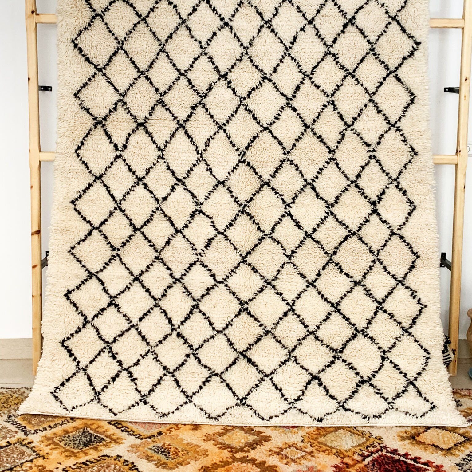 Tapis artisanal écru conçu par Afusart, tissé à la main par Malika, avec motifs amazighs noirs et touches colorées.