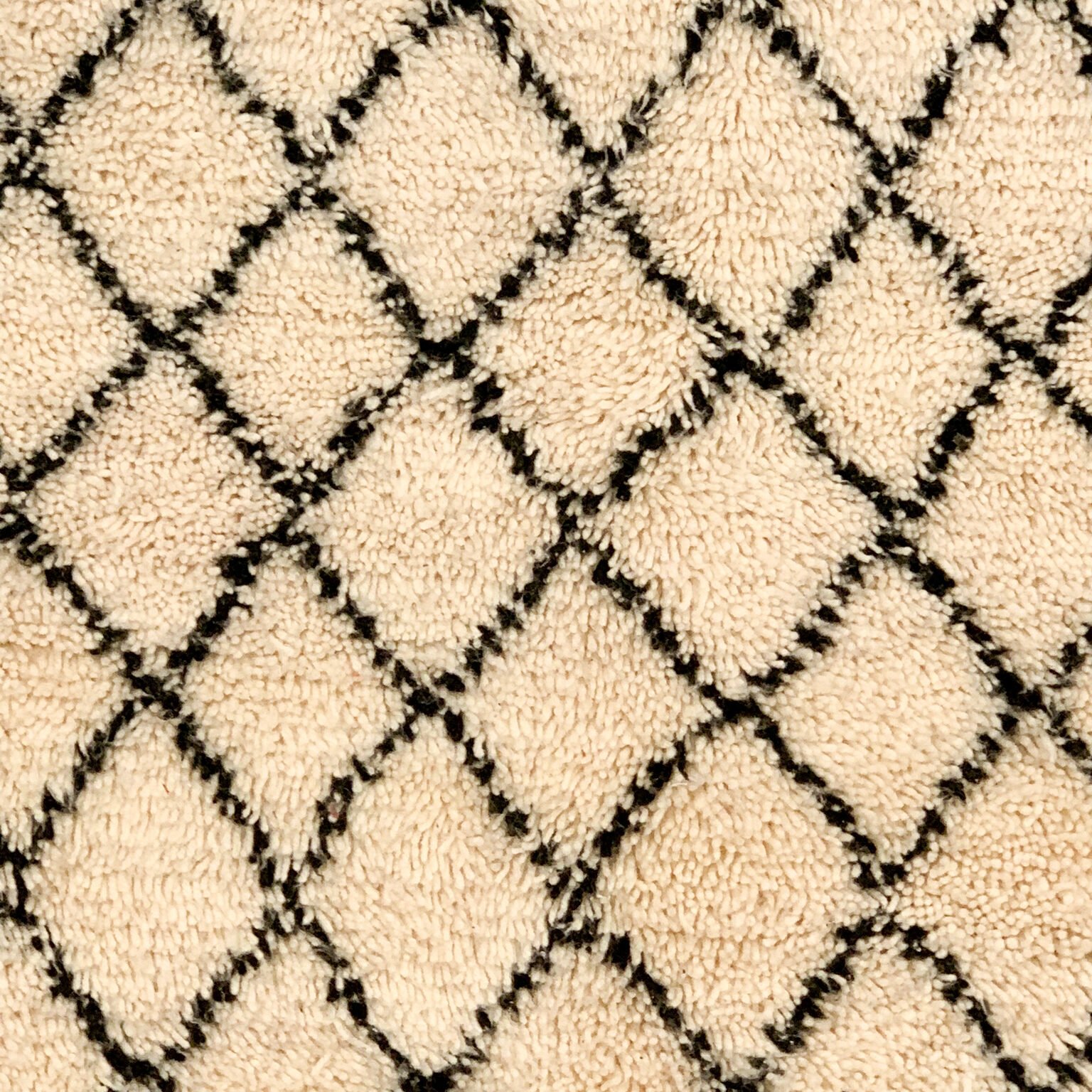 Tapis artisanal écru conçu par Afusart, tissé à la main par Malika, avec motifs amazighs noirs et touches colorées.