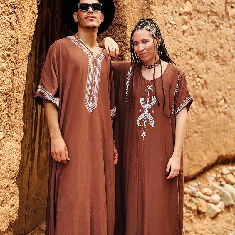 Homme et femme portant une gandoura amazighe marron Afusart, ornée de motifs graphiques inspirés de la culture amazighe.