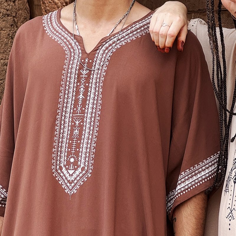 Homme portant une gandoura amazighe marron Afusart, ornée de motifs graphiques inspirés de la culture amazighe.