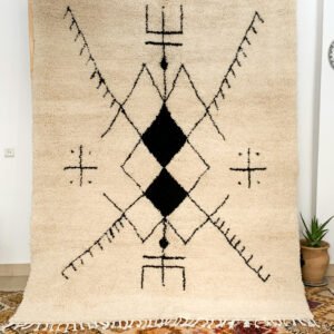 Tapis artisanal écru conçu par Afusart, tissé à la main par Malika, avec motifs amazighs noirs et touches colorées.