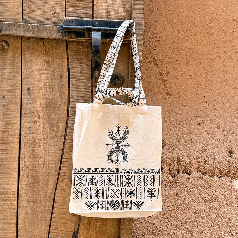 Tote bag beige au design unique Afusart, avec longues et petites anses décorées de motifs amazighs noirs.