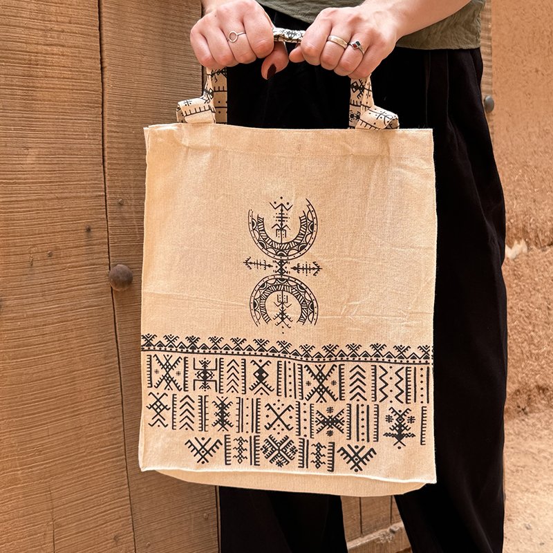 Tote bag beige au design unique Afusart, avec longues et petites anses décorées de motifs amazighs noirs.