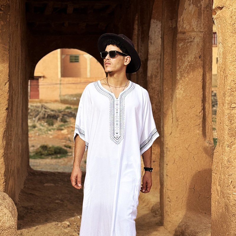 Homme portant une gandoura amazighe blanche Afusart, ornée de motifs graphiques inspirés de la culture amazighe.