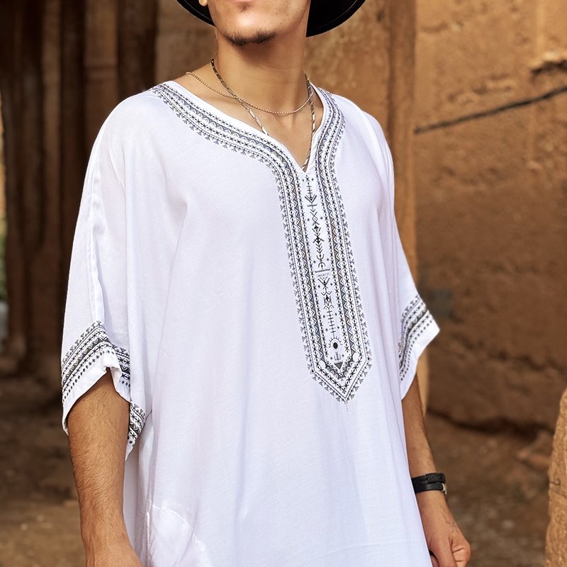 Homme portant une gandoura amazighe blanche Afusart, ornée de motifs graphiques inspirés de la culture amazighe.