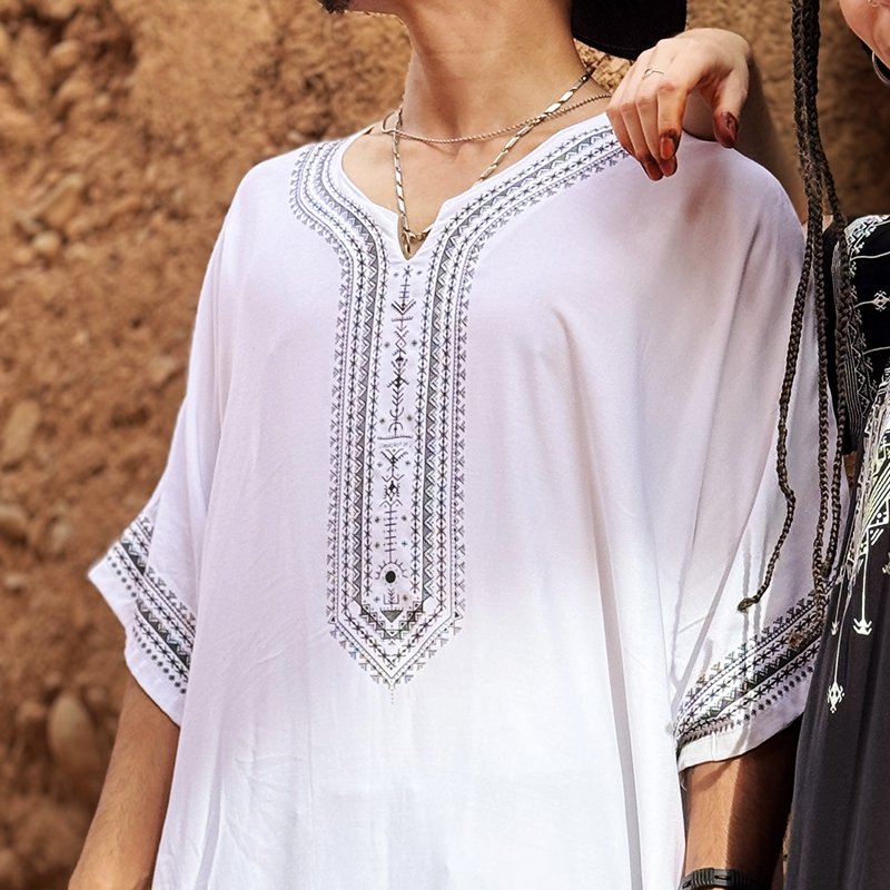 Homme portant une gandoura amazighe blanche Afusart, ornée de motifs graphiques inspirés de la culture amazighe.