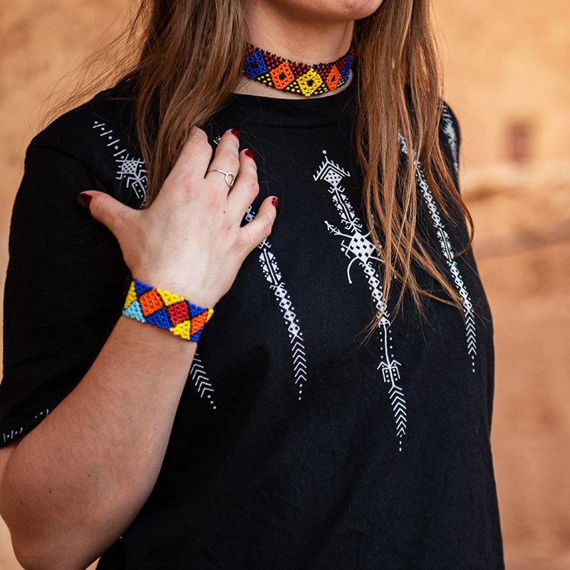 Black Amazigh crop top featuring white geometric decorative motifs on the front, shoulders, and sleeves