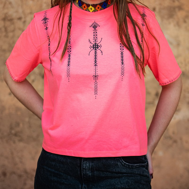 Bright pink Amazigh crop top with black geometric decorative motifs on the front, shoulders, and sleeves