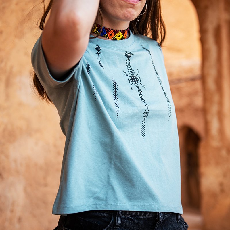 Light green Amazigh crop top featuring black geometric motifs and AZA symbols on the front