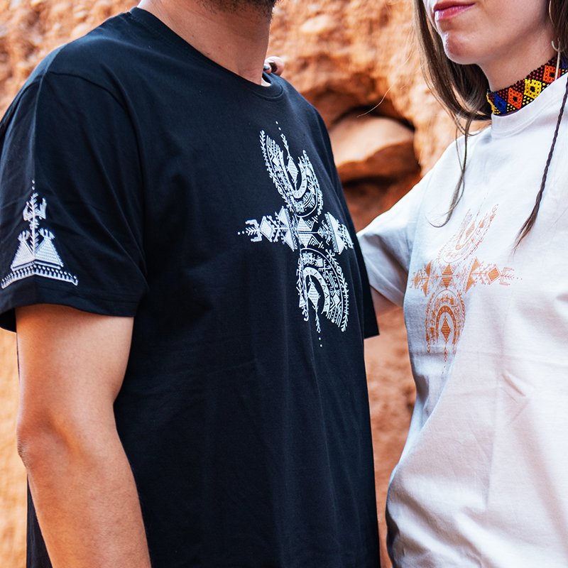 Homme et femme portant des t-shirts Afusart noir et blanc, ornés d’un design amazigh inspiré du symbole de liberté Aza.
